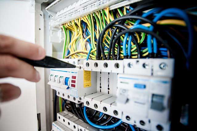 Electrician troubleshooting wiring inside an electrical panel